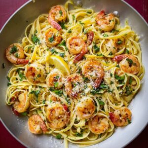 Shrimp linguine with garlic butter sauce, parsley, and lemon wedges in a white bowl