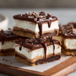 No-bake chocolate cream cheese bars cut into squares with chocolate cookie crust, fluffy cream cheese filling, and chocolate ganache top