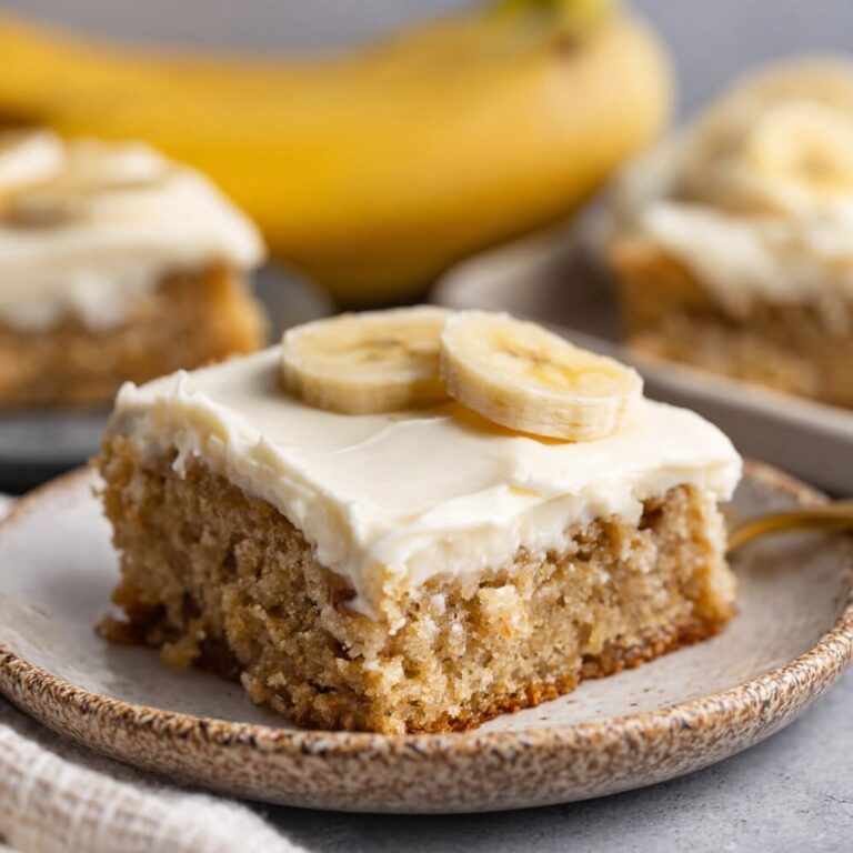 Banana bars cut into squares with thick fluffy cream cheese frosting, golden moist banana cake, and chopped walnuts on top
