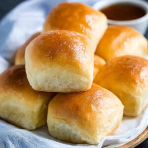Texas Roadhouse rolls with golden buttery tops, sweet brioche-like interior, served with cinnamon honey butter spread on the side