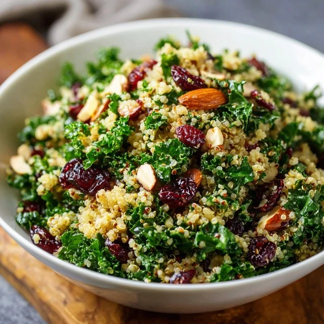 Close-up of quinoa kale salad showing fluffy mixed-color quinoa grains, soft massaged kale ribbons, juicy ruby cranberries, crumbly feta chunks, scattered toasted almond slivers